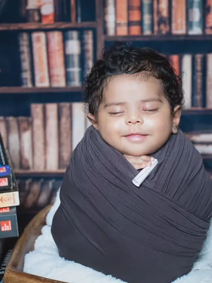 A peaceful smile from our future genius, swaddled and ready to absorb all the knowledge from the books around him.
