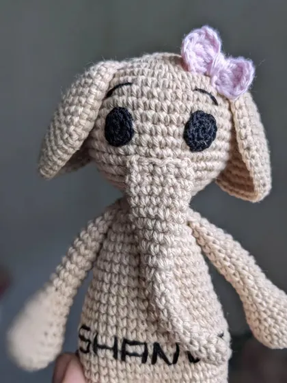 A close-up of the personalized name 'SHANVI' embroidered on the belly of a handmade elephant doll.