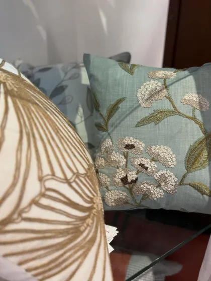 The sunlight catches the beautiful details of our embroidered cushions. This shot highlights the texture of the threadwork, from the bold, graphic pattern on the left to the delicate floral design on the right.