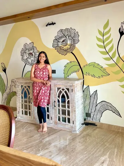 Standing with a finished floral mural. This piece was designed around the client's existing furniture, integrating the artwork seamlessly into their home decor.