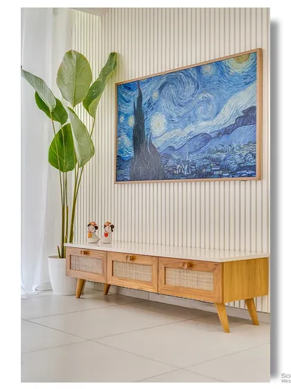 A minimalist TV console made of light wood with rattan-fronted drawers. A large print of Van Gogh's "Starry Night" adds a dramatic splash of color and artistry to the otherwise neutral space.