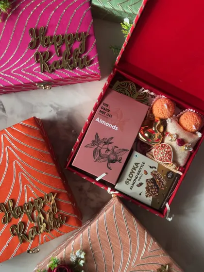 A beautiful flat lay of my fabric-covered Rakhi gift boxes, filled with almonds, almond brittle, and a bhaiya-bhabhi rakhi set.