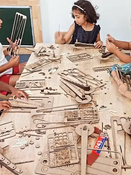Something's cooking at the school camp! A table full of busy hands as students work on assembling intricate wooden mechanical kits.