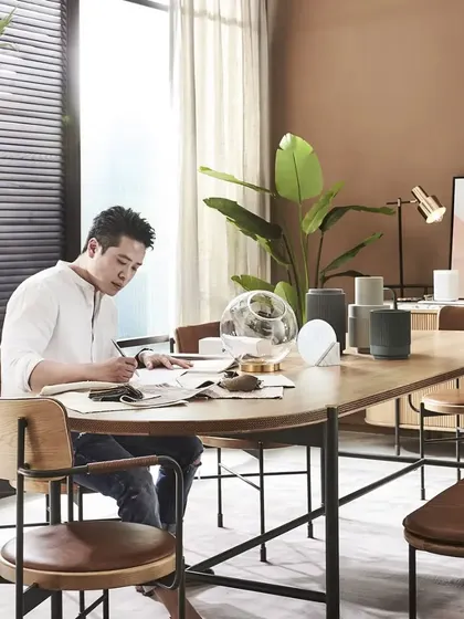 A person at work at the Tierra Dining Table. This image showcases the versatility of our furniture, which is designed to be a beautiful and functional part of your everyday life, whether for dining, working, or creating.