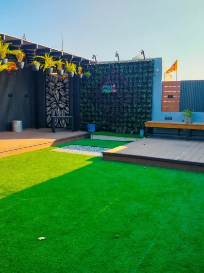 A completed terrace garden in Uttam Nagar, New Delhi. This daytime shot shows the artificial lawn, raised wooden decks, and vertical gardens.