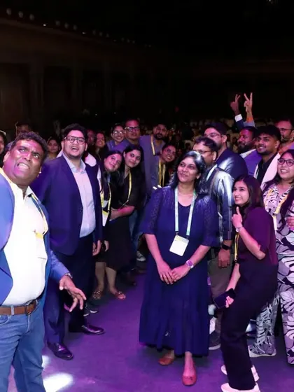 An attendee takes a selfie with a group on stage, showing the celebratory and social side of the UXINDIA conference.