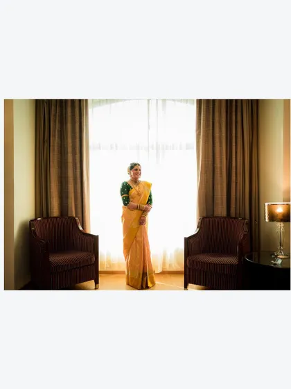 A wide shot of the bride standing alone in a beautifully decorated room, a moment of quiet contemplation.
