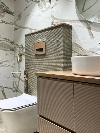This angle highlights the clean lines of the floating vanity and the vessel sink. The round mirror softens the look, while the marble-patterned tiles add a touch of drama.
