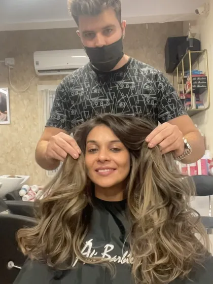 A happy client showing off her new, voluminous blonde hair.