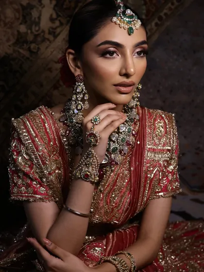 A side profile that captures the elegant hair updo adorned with a fresh rose, and the beautiful contouring of the cheekbones.