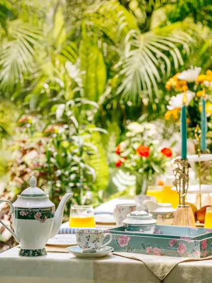 A wide shot of a tea set and serving tray from Vigneto, placed in a bright, sun-drenched garden. This image creates a strong feeling of a peaceful, leisurely afternoon.