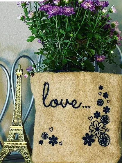 Sometimes, the simplest message is the most powerful. This jute grow bag, embroidered with the word 'love' and a floral design, turns a simple flowering plant into a heartfelt gift for someone special.