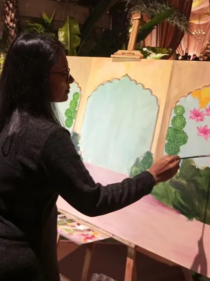 Here I am at my easel, adding the first layers of color to the background. This is the foundational step before I paint the couple into their beautifully decorated wedding scene.