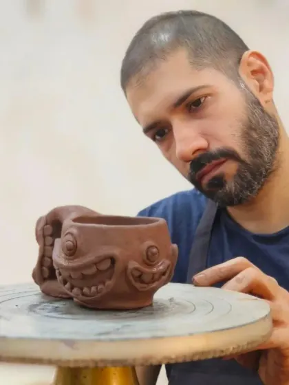 A student puts the finishing touches on a quirky, monster-faced mug. Hand-building is perfect for creating fun, sculptural pieces with unique personalities.
