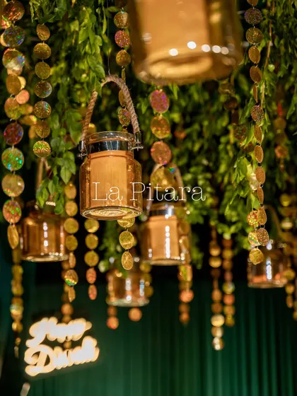 A detail of the ceiling decor, featuring hanging glass lanterns and shimmering sequin garlands interspersed with greenery. This created a magical, starry-night effect above the party.