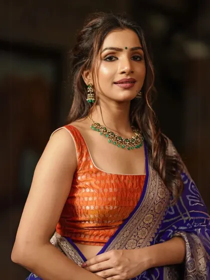 An orange brocade blouse is beautifully complemented by a simple green beaded necklace, showcasing a vibrant and contrasting color combination.