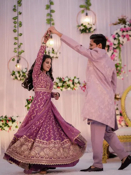 The couple shares a dance at their engagement party, the bride's purple Anarkali twirling beautifully as her partner leads her.