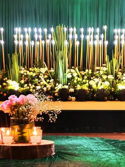 A close-up of an elegant Sangeet stage backdrop, featuring a wall of lights, lush greenery, and white flowers.