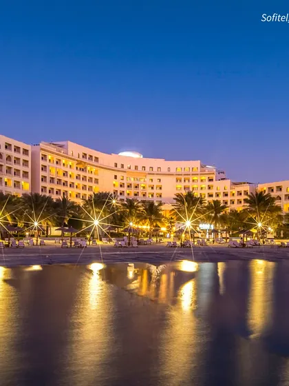 The Sofitel Bahrain at night, with its lights reflecting on the water. A beachfront destination wedding offers a magical ambiance that is simply unparalleled.