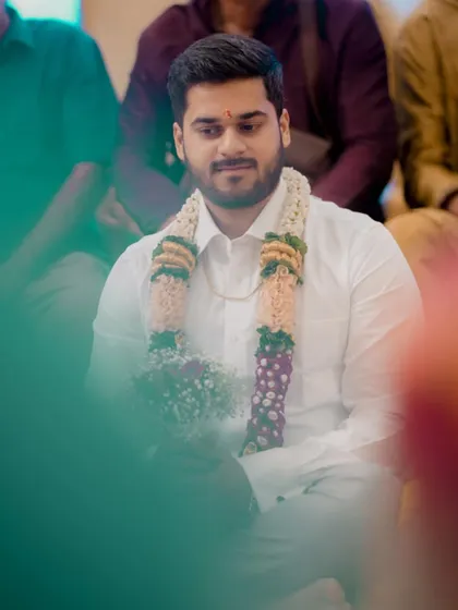 An artistic shot of the groom, seen through a soft foreground blur, creating a dreamy and contemplative portrait.