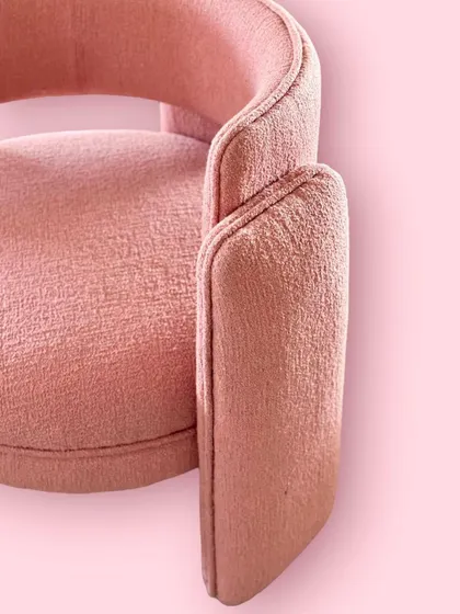 The rich texture of coral bouclé fabric is on full display in this close-up of our "Pebble" chair. The clean piping detail defines the chair's sculptural form.