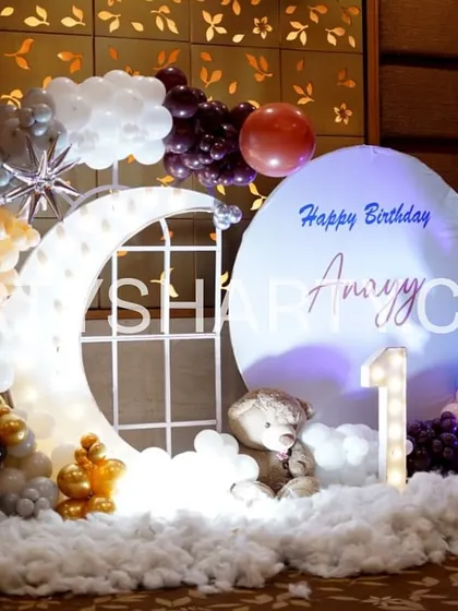 A charming photo corner with a lighted moon prop, a teddy bear sitting on fluffy clouds, and a balloon arrangement in a beautiful color scheme.