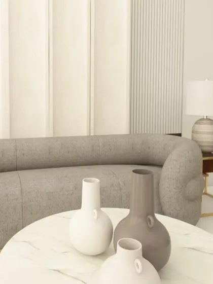 The details matter. This shot focuses on the soft, rounded form of the sofa against the textured wall, with decorative vases adding a final touch.