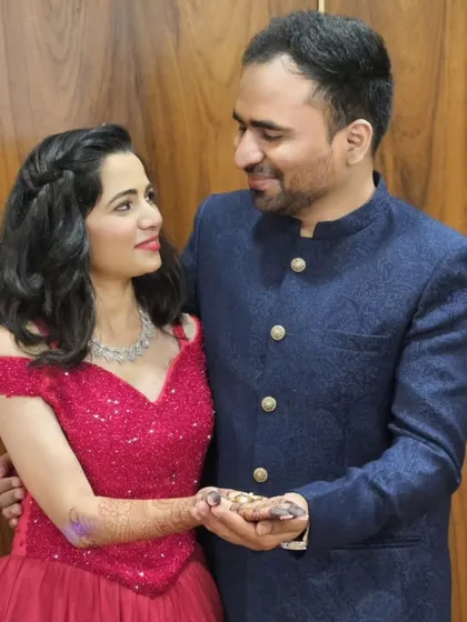 A close-up of the ring exchange. The bride's sparkling red off-shoulder gown adds a touch of glamour and romance to their beautiful ring ceremony.