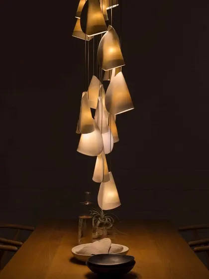 A small, intimate cluster of Bocci 21 pendants over a dining table. The light filtering through the thin porcelain creates a warm and inviting atmosphere, perfect for quiet dinners.