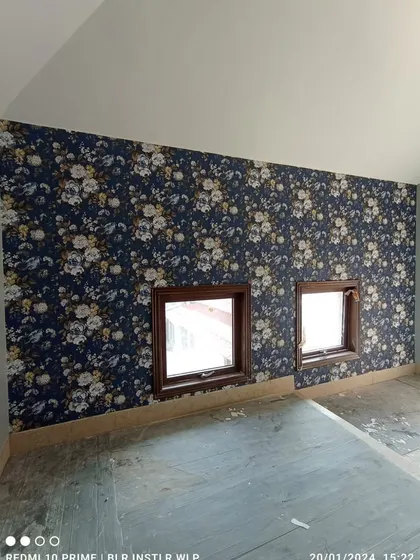 A dark blue floral wallpaper installed in a room with small windows.