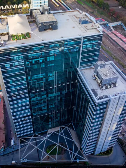 An aerial drone shot of Naman Midtown, a 700,000 sq. ft. commercial building we completed in Elphinstone Road, Mumbai. The view highlights the building's massing, rooftop amenities, and its strategic location adjacent to key transportation infrastructure.