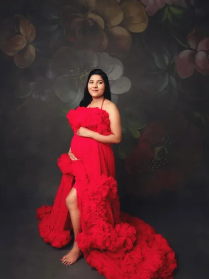 Posed against a floral painted backdrop, this mom-to-be in a ruffled red gown looks like a classic work of art.