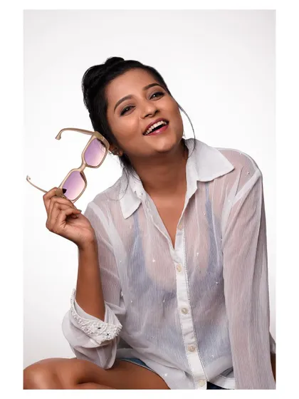 A fun and happy portrait of a model in a sheer white shirt and sunglasses. Her bright smile is infectious, creating a joyful and lighthearted image.