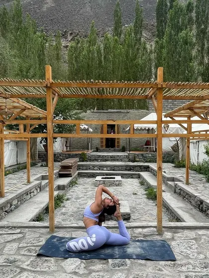 A deep King Pigeon Pose in a serene courtyard in Ladakh. This posture is a primary focus for clients wanting to improve hip flexibility and open their quadriceps.
