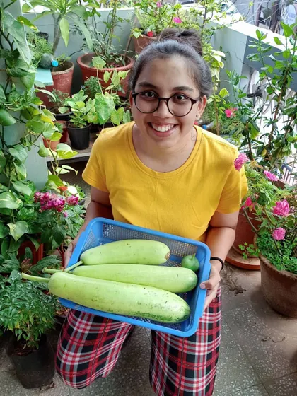 Me with my harvest of bottle gourds, sitting happily in my balcony garden. From terrace to balcony, my plants are everywhere.