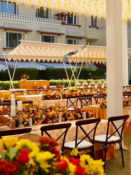 A wide view of the outdoor dining setup, with long tables adorned with flowers, set under elegant tents for a festive lunch.