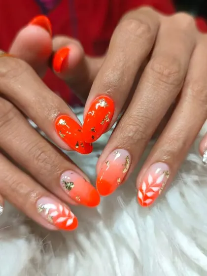 A vibrant orange ombre set decorated with delicate white leaf patterns and shimmering gold foil flakes.
