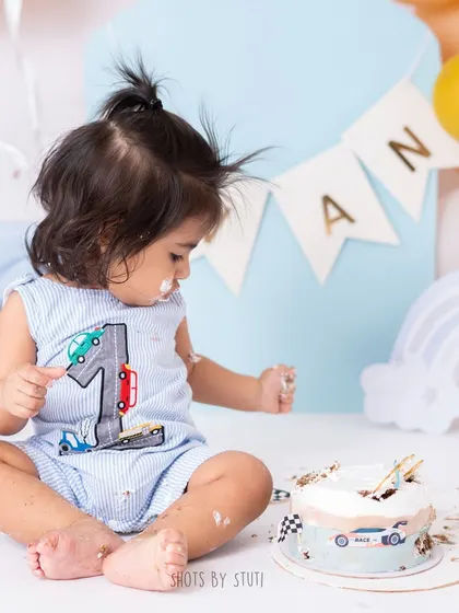 This little racer is just getting started on his cake demolition. The car-themed setup with a custom cake adds a personal touch that makes his first birthday photos extra special.