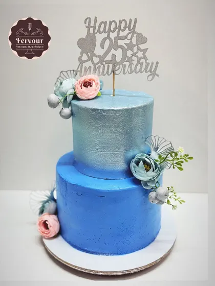 A 25th anniversary cake in a beautiful silver and blue ombre design. The metallic sheen on the top tier and delicate floral placements make this a perfect centerpiece for celebrating a silver jubilee.