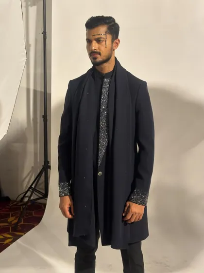 A backstage shot before the show, capturing the full details of the layered outfit and the makeup.