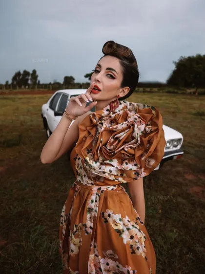 This image from 'BLANCH' showcases the custom-designed floral dress in an open field. The styling aims to create a sense of cinematic drama, as if capturing a single frame from a classic film.