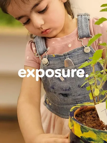 A close-up of a child holding her finished plant. The word "exposure" overlaid on the image reinforces our goal of providing new and enriching experiences.