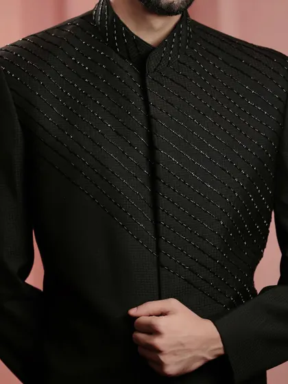 A detailed shot of the hand-beaded panel on the black Indo-Western jacket. The precision of the work adds a textural element that elevates the entire garment.