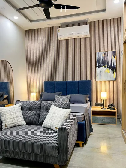 A modern bedroom design featuring a fluted wooden panel behind a deep blue upholstered bed. The combination of textures and colors creates a contemporary yet cozy ambiance.