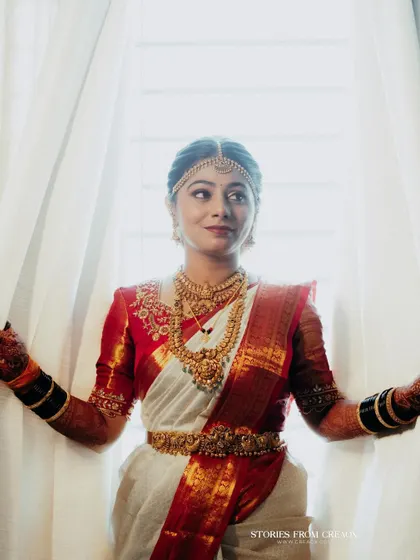 A beautiful window-lit portrait of the bride. The soft, natural light highlights the flawless finish of her makeup and the intricate details of her bridal attire.