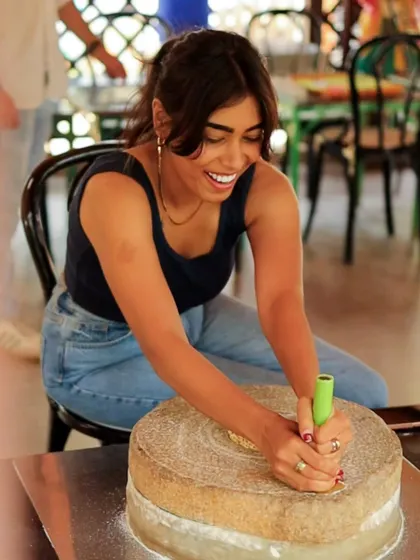 A guest smiles as she tries her hand at grinding grains with a traditional stone grinder, another one of our unique, hands-on cultural activities.