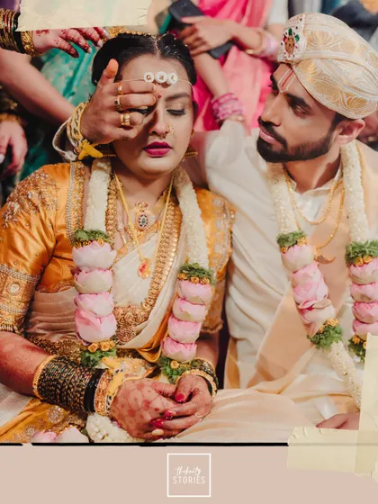 A sacred moment during the wedding ceremony. The groom's gesture of care towards his bride is a beautiful, candid capture of their connection amidst the rituals.