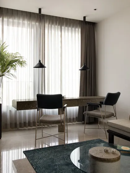 The multipurpose room includes a clean, clutter-free workstation for two. The floating desk is placed in front of a large window to maximize natural light, creating a serene and productive environment.
