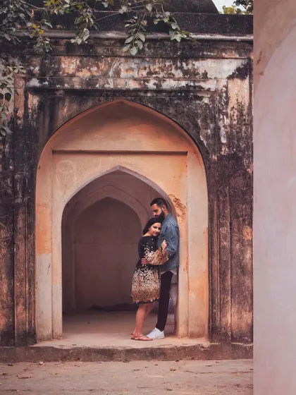 A wider shot that captures the beautiful architecture of Lodhi Garden. The historic setting provides a stunning backdrop for their modern love story.