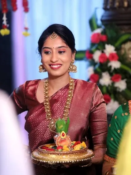 All smiles and ready for the ceremony. This photo shows the complete look with a simple maang tikka and jhumkas, perfect for a daytime family wedding event.